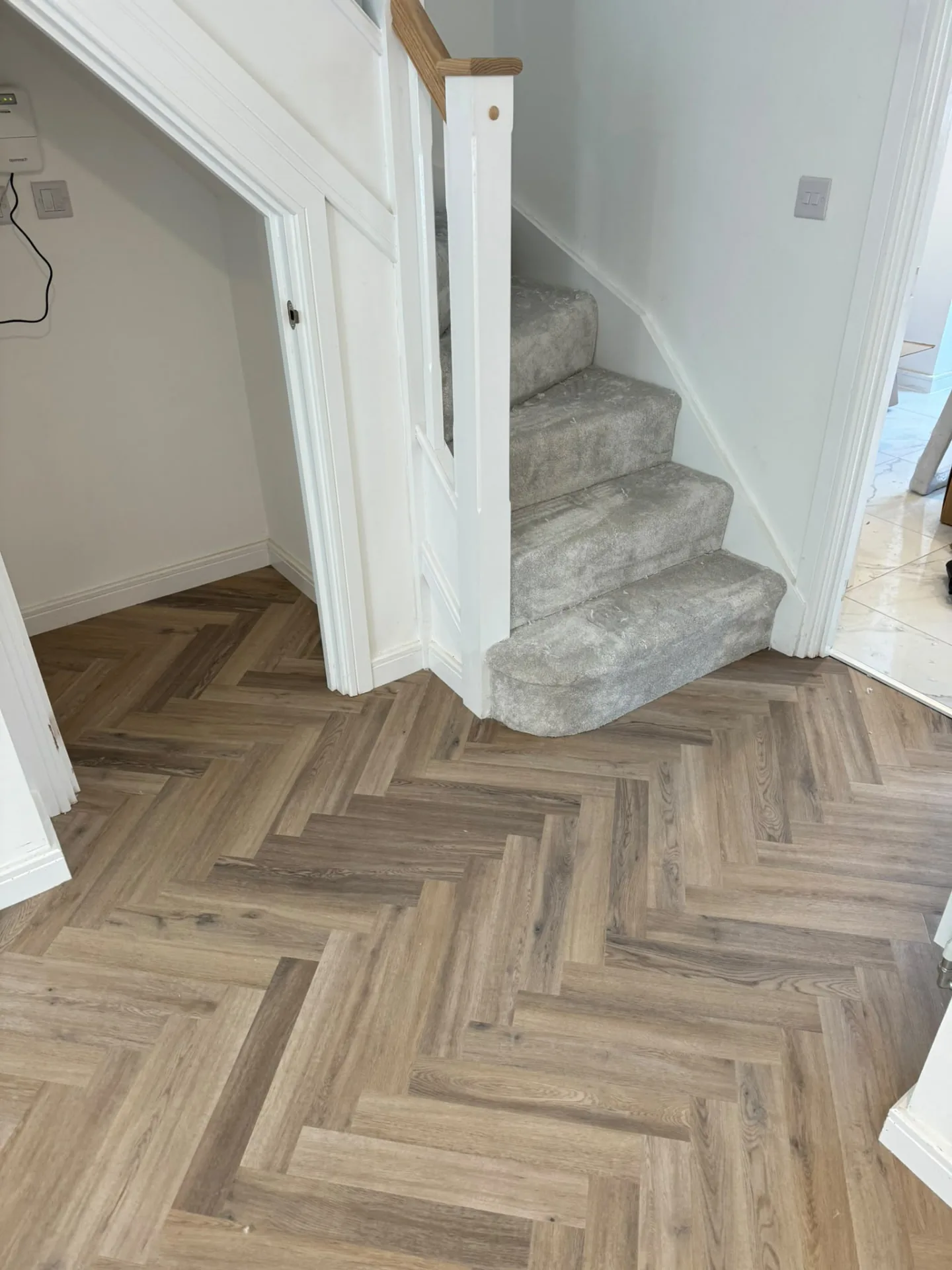 Herringbone LVT hallway floor fitted around a carpeted bullnose stair, Signature Carpets and Flooring, Greater Manchester