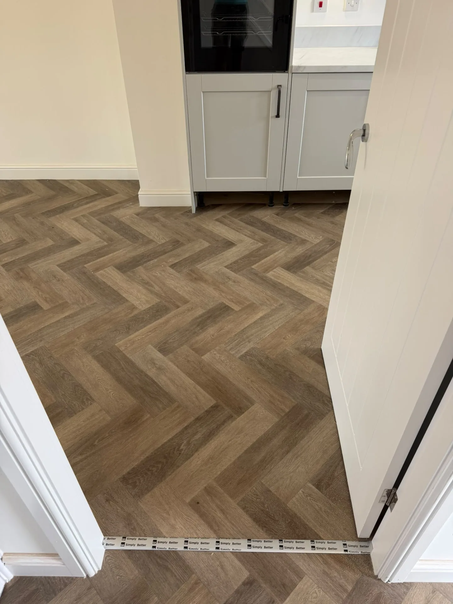 Dark oak herringbone vinyl flooring fitted in a kitchen, Signature Carpets and Flooring, Greater Manchester