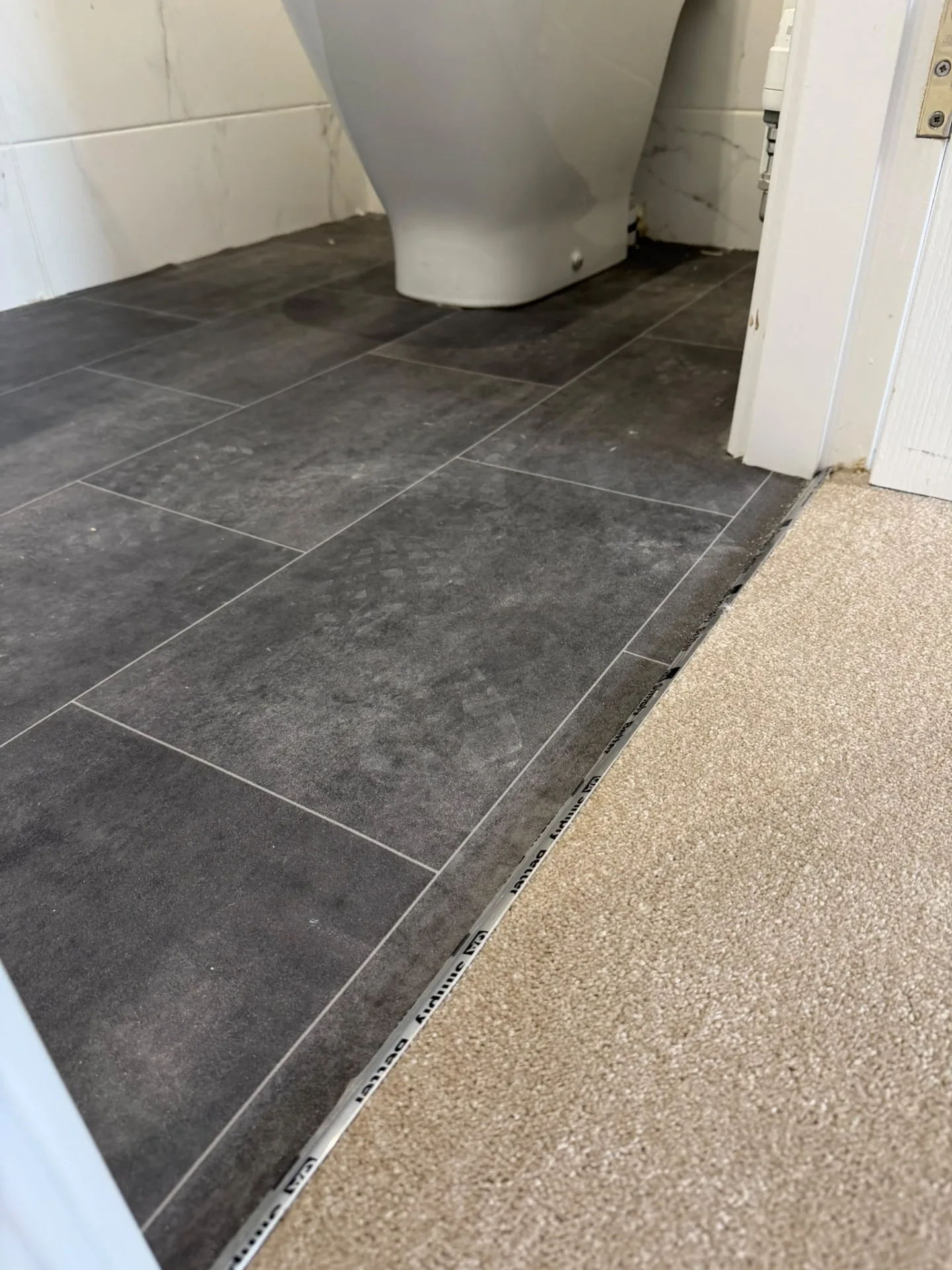 Tile-effect bathroom vinyl finished with a threshold strip to carpet, Signature Carpets and Flooring, Greater Manchester