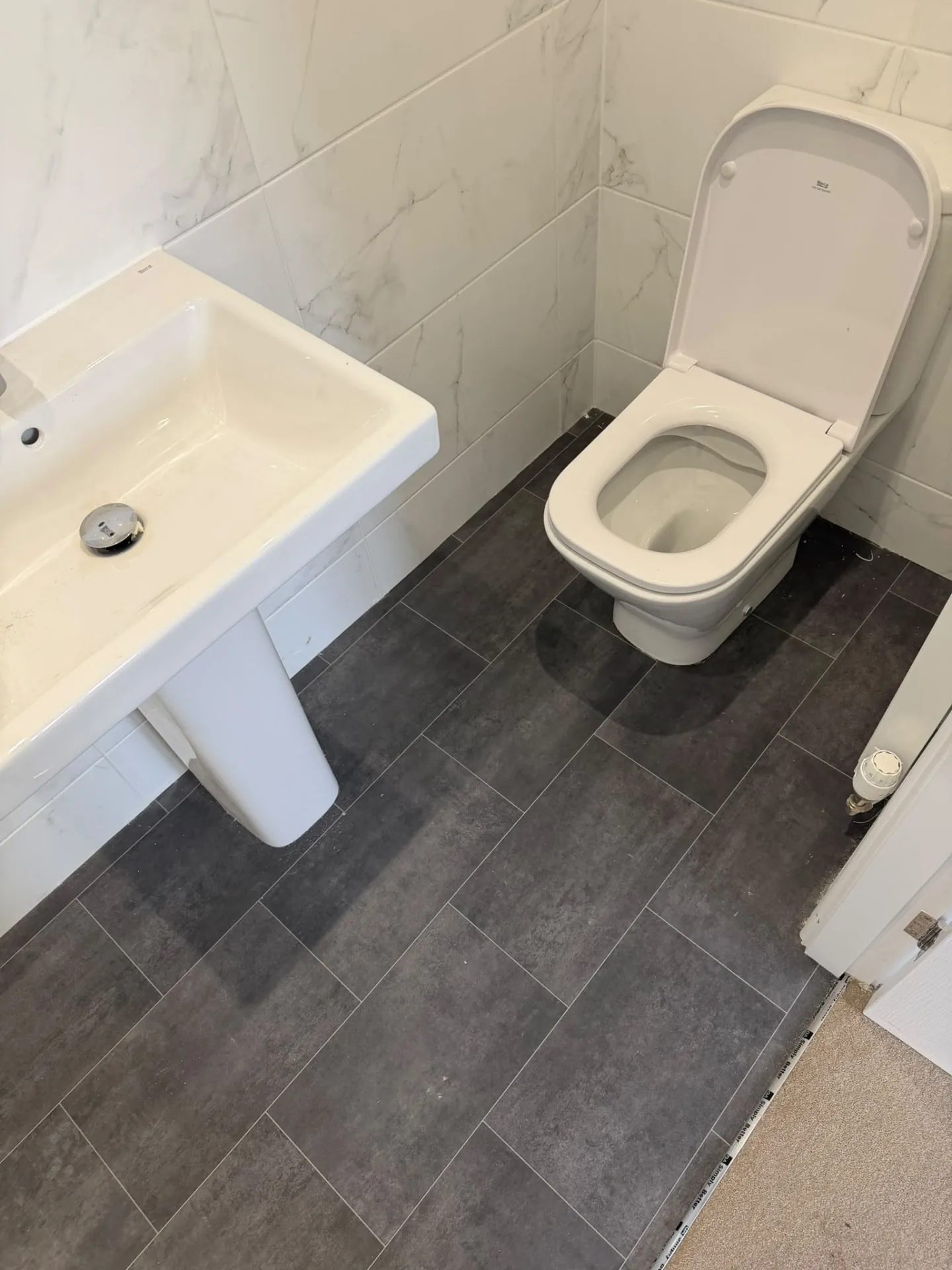 Dark tile-effect vinyl bathroom floor fitted around the toilet and basin, Signature Carpets and Flooring, Greater Manchester