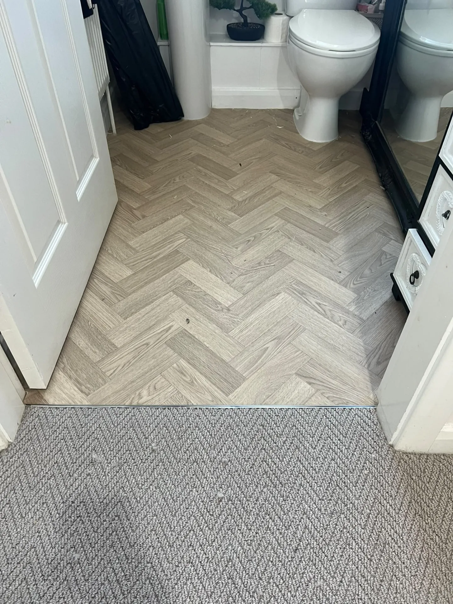 Light herringbone vinyl bathroom floor with a metal threshold to carpet, Signature Carpets and Flooring, Greater Manchester