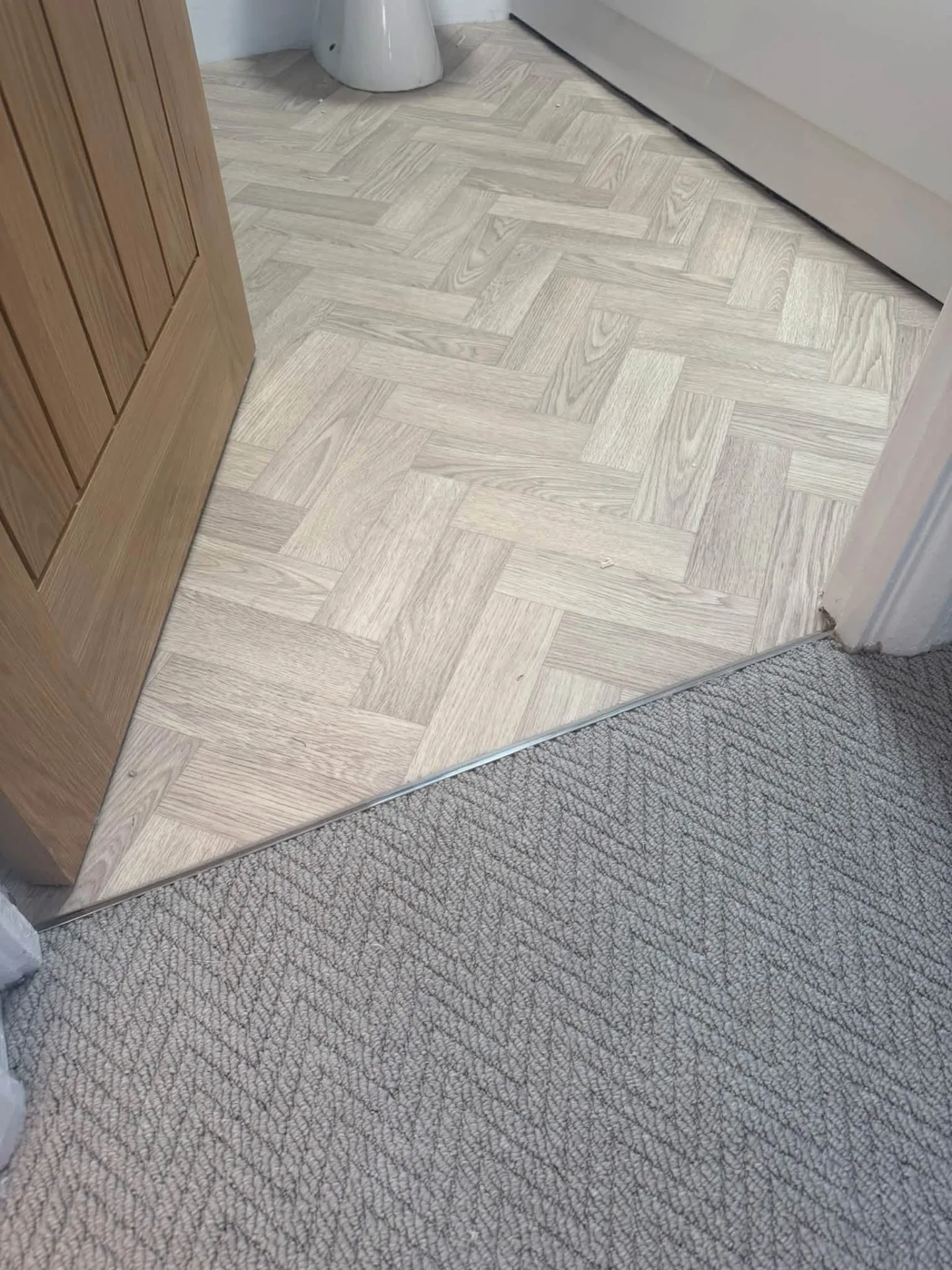 Herringbone bathroom vinyl joined to landing carpet with a metal trim, Signature Carpets and Flooring, Greater Manchester